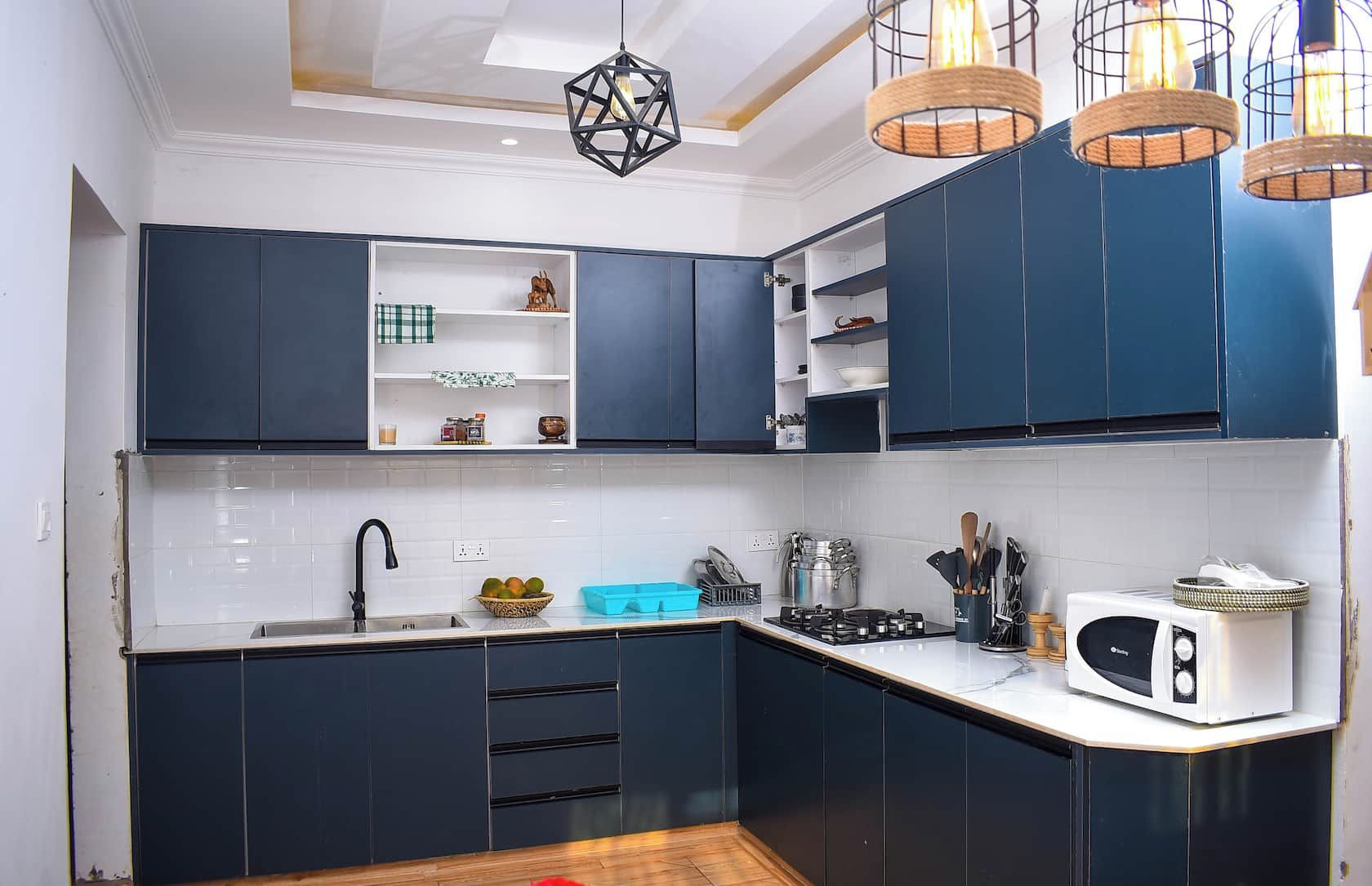Une cuisine moderne avec des meubles de couleur sombre, un plan de travail blanc et une cuisinière intégrée.