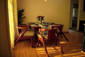 Un coin repas avec une table en bois dressée pour quatre personnes, entourée de quatre chaises.