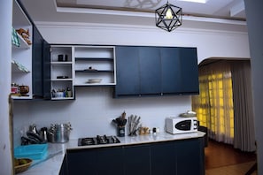 Une cuisine avec des meubles de couleur sombre, un four à micro-ondes et une cuisinière à gaz.