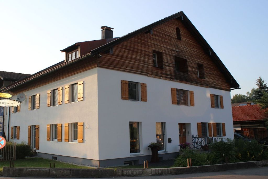 A two-story building with a white facade and wooden upper section.