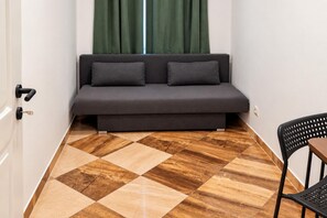 Ein Zimmer mit einer Couch, einem Sessel und einem Musterparkett.