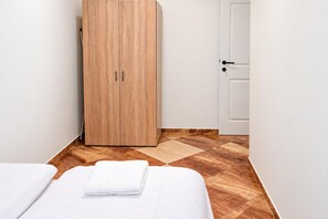 A hotel room with a wooden wardrobe, a bed with white linens, and a checkered floor. - Vienna Days Sofa Nights 1BR near Westbahnhof (Vienna)