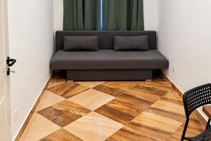 A room with a sofa against a wall, a door, and a patterned floor. - Vienna Days Sofa Nights 1BR near Westbahnhof (Vienna)
