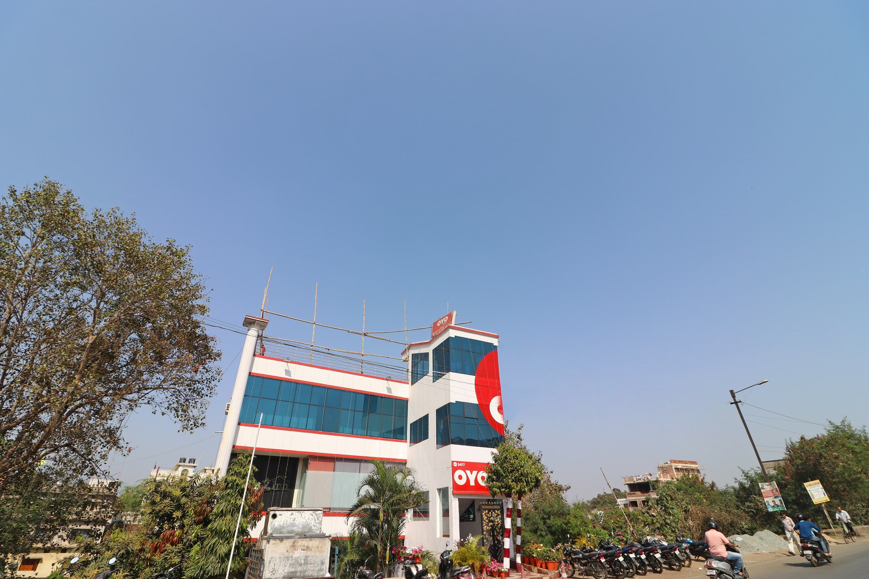 Un edificio con un letrero rojo y blanco llamativo, rodeado de árboles y motocicletas estacionadas.