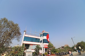 A building with a prominent red and white sign, surrounded by trees and parked motorcycles. - Hotel O Misti Inn (Jamshedpur)