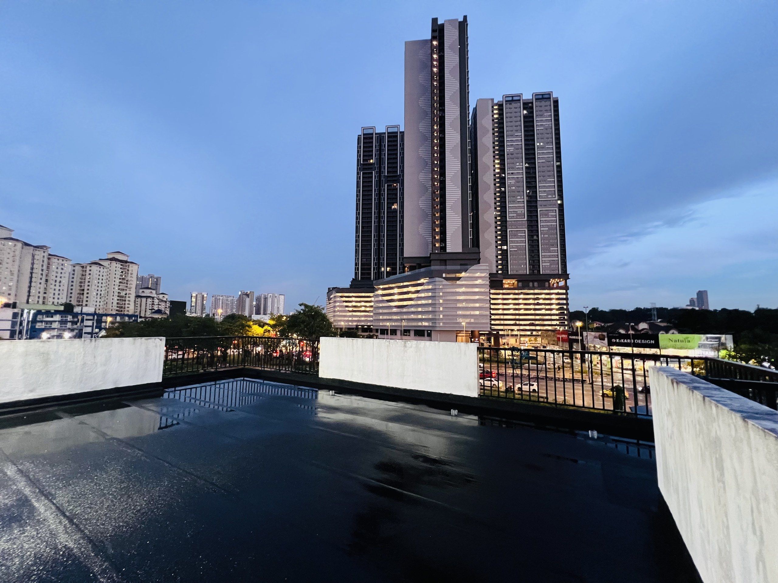 Un edificio moderno de gran altura con fachada de vidrio reflectante, rodeado de otros edificios y un cielo despejado.