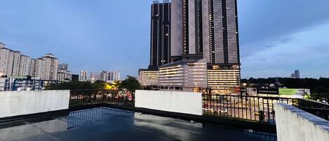 A modern high-rise building with a reflective glass facade, surrounded by other buildings and a clear sky.