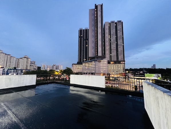 A modern high-rise building with a reflective glass facade, surrounded by other buildings and a clear sky.