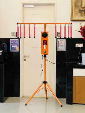 A room with a door, a desk with a computer, a poster offering free WiFi, and a stand with pink tubes.