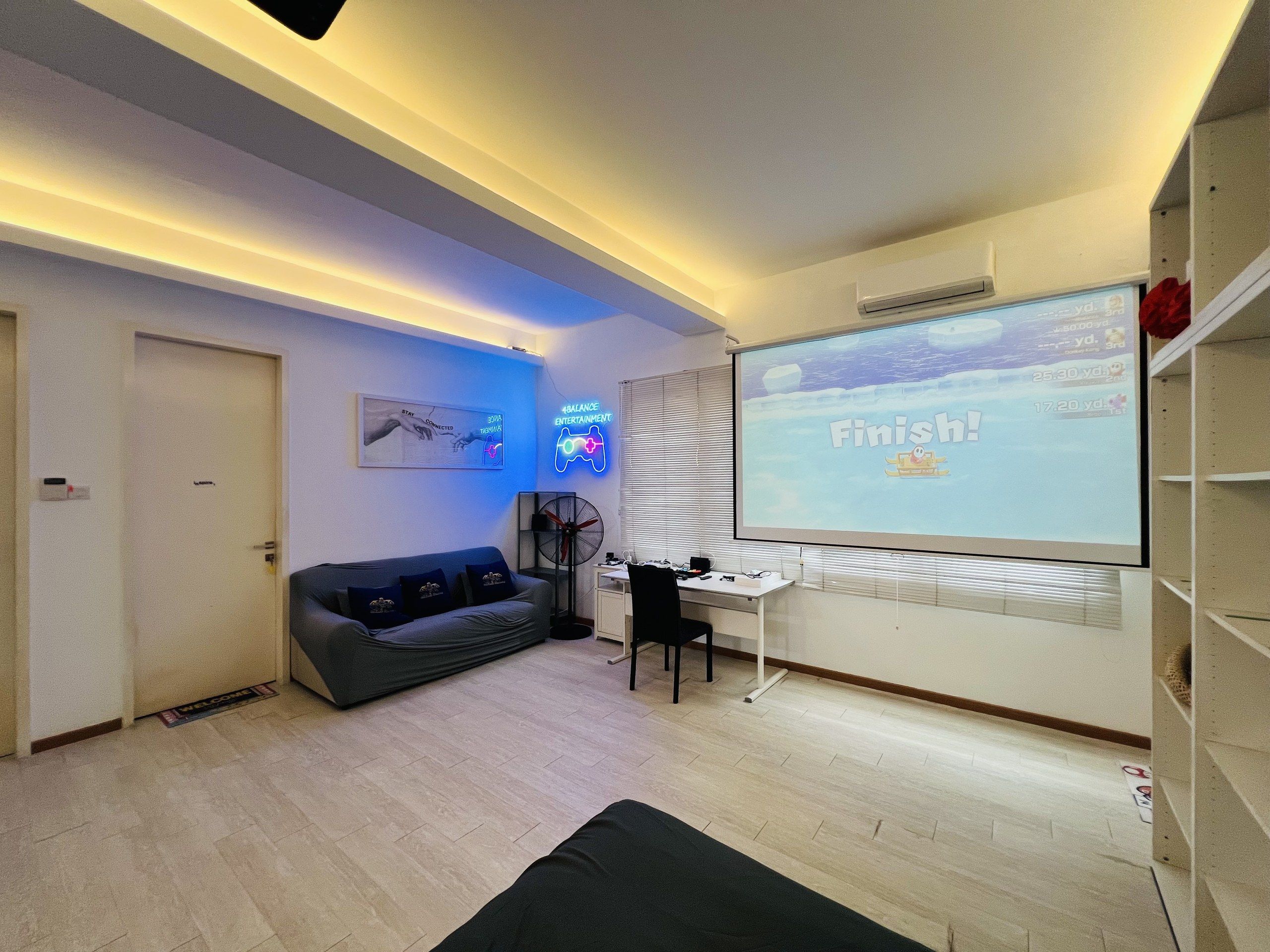 Un salon moderne avec un canapé, un bureau et un écran de projection affichant le mot « Terminé ! » sur un mur.