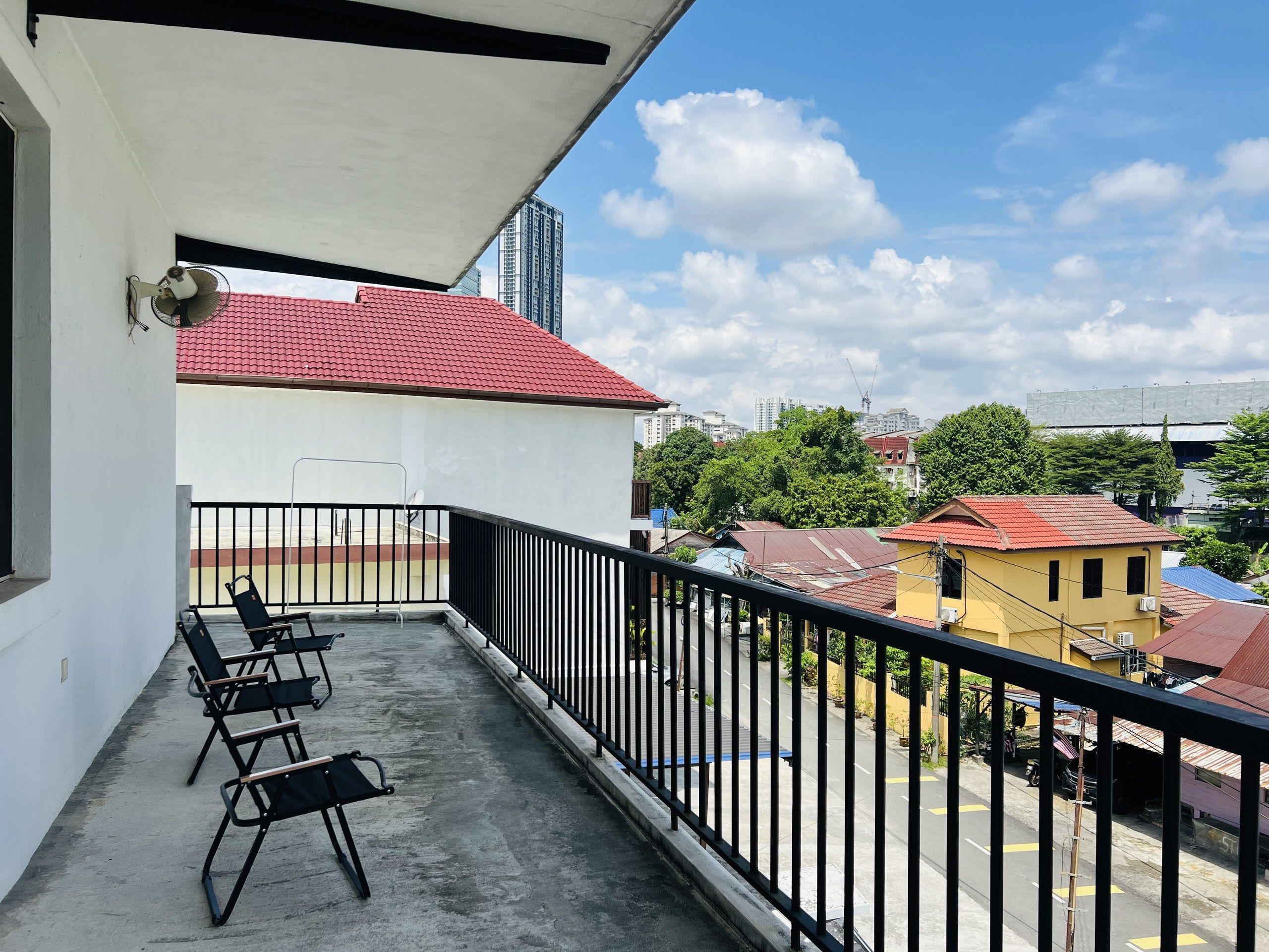 A balcony with a concrete floor, black metal railing, and black chairs.