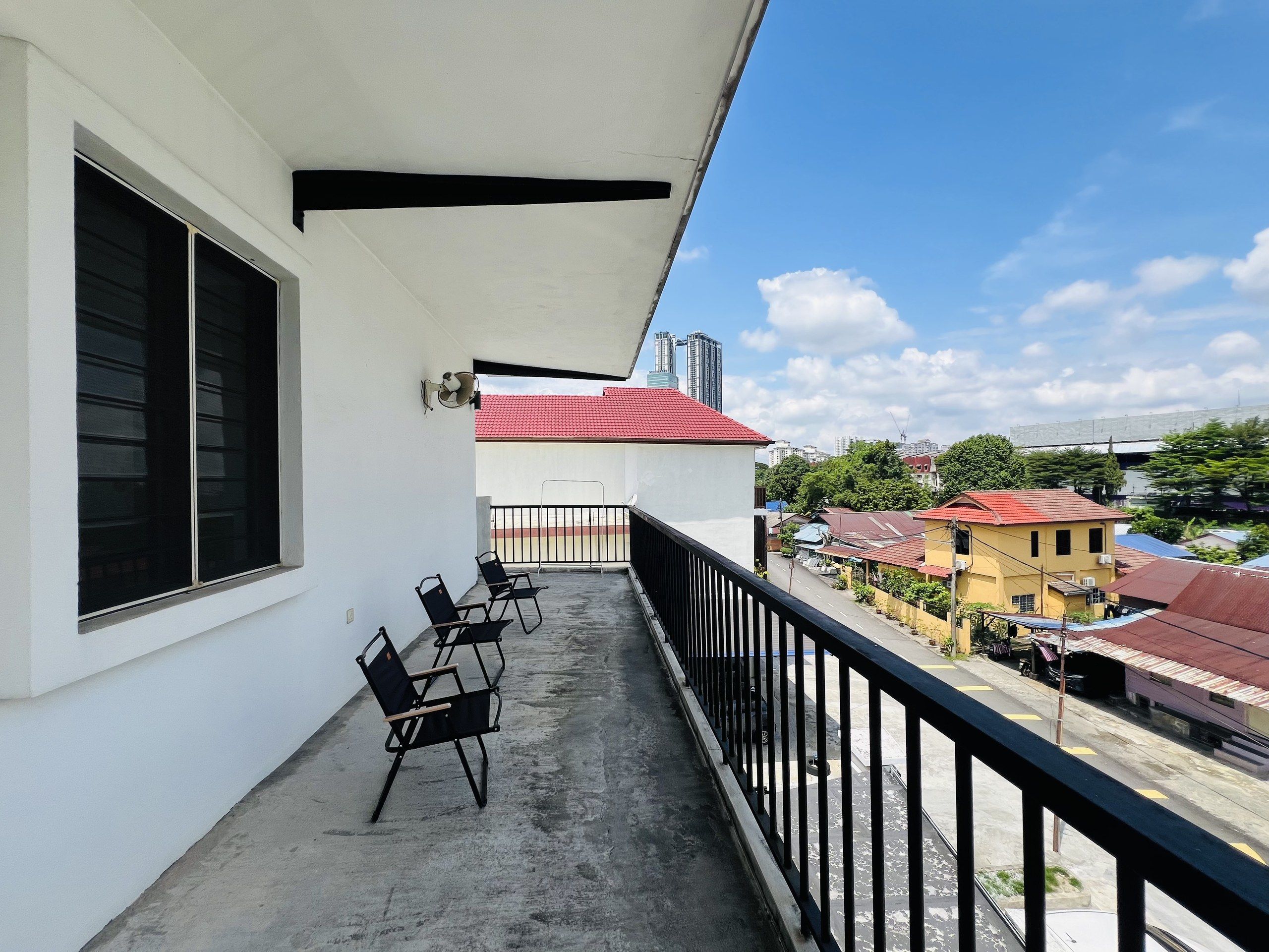 Un balcon offrant une vue sur le paysage urbain, avec des bâtiments et un ciel dégagé.