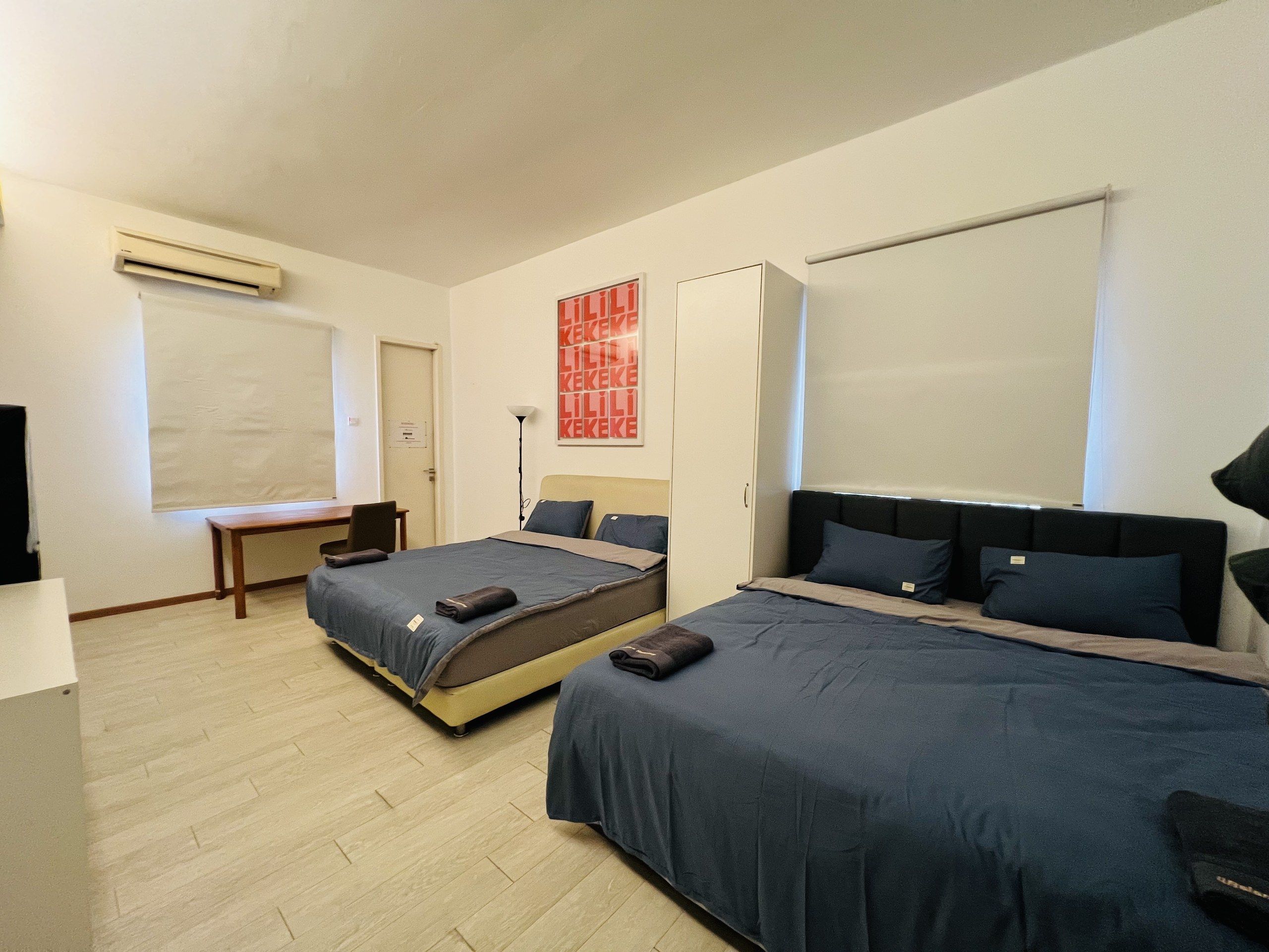 Une chambre d’hôtel avec deux lits, un bureau, une chaise, une armoire et un téléviseur.