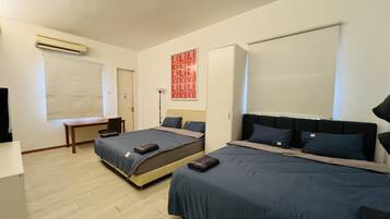 Une chambre d’hôtel avec deux lits, un bureau, une chaise, une armoire et un téléviseur.