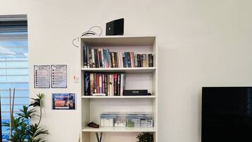 Une bibliothèque blanche avec des livres, un téléviseur et des objets de décoration.