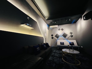 A modern lounge area with a sofa, a round table, and a wall-mounted projector.