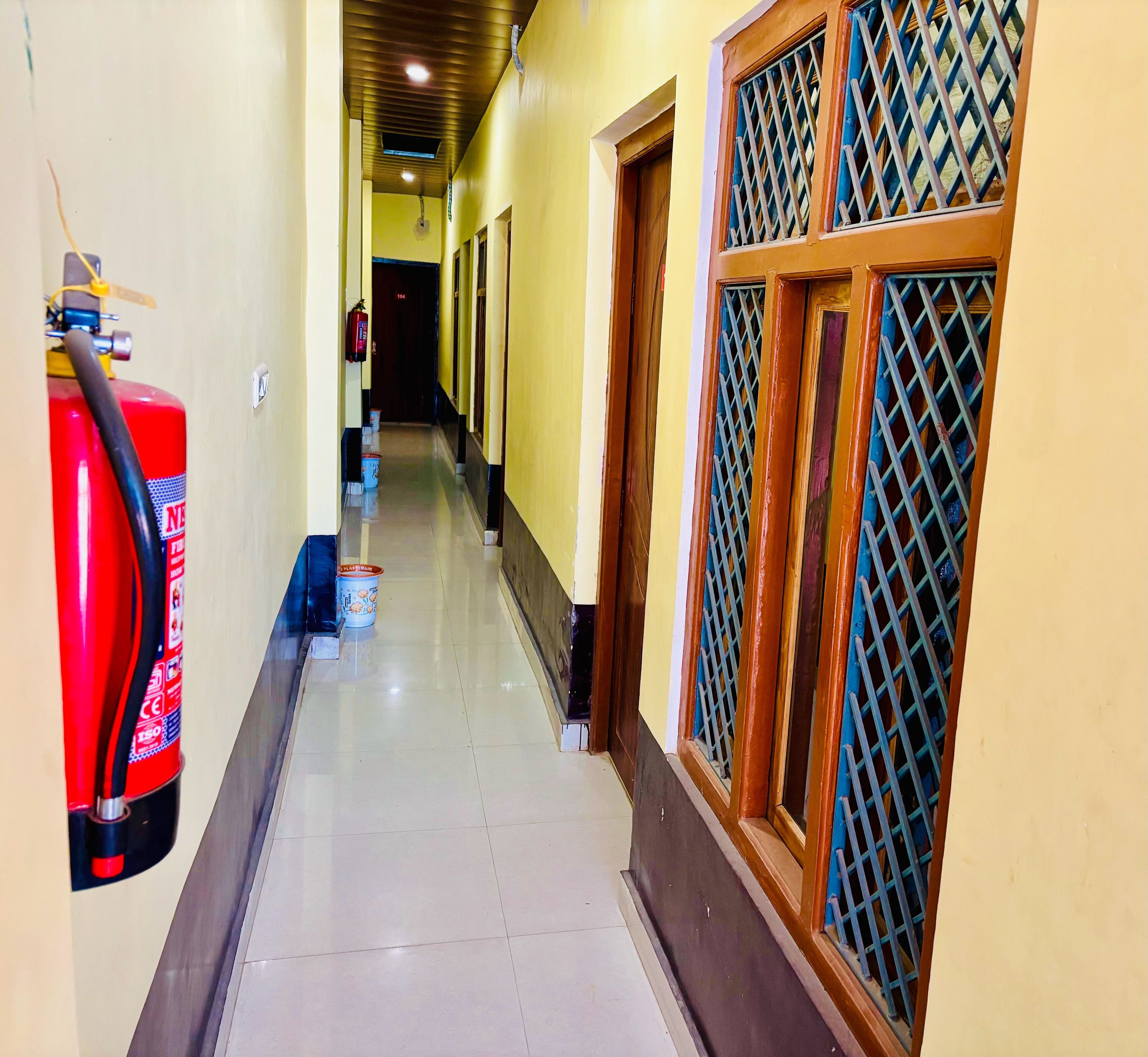 A corridor with a fire extinguisher, a bucket, and a door with a metal grille.
