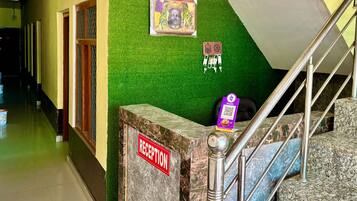 A reception area with a marble reception desk, a staircase with metal railings, and a green wall with a framed picture.