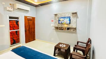 A bedroom with a bed, a TV mounted on the wall, a ceiling fan, and a wooden door.