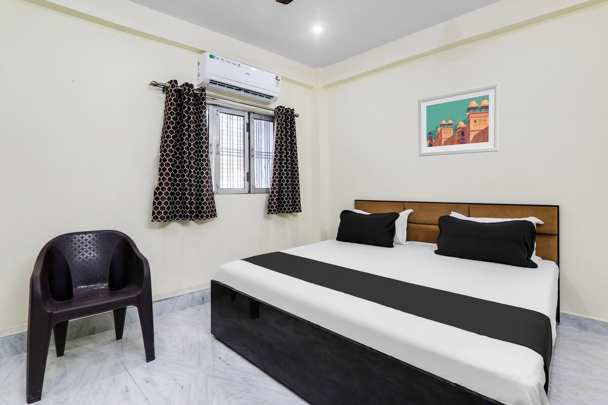 Habitación de hotel con cama, una silla, equipo de aire acondicionado y un cuadro en la pared.