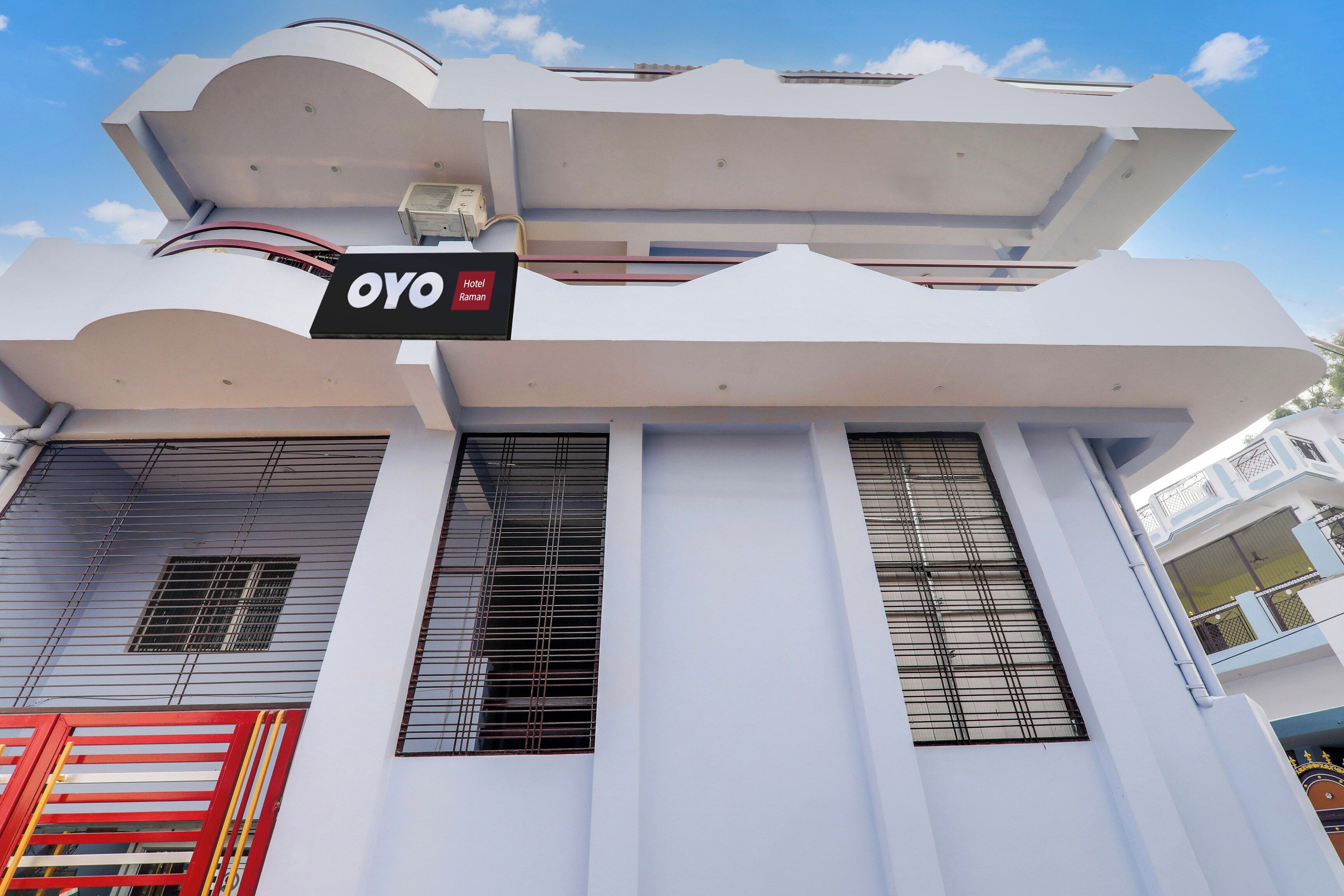 Ein Hotel namens 'OYO Hotel Raman' mit moderner Architektur, das sich durch markante vertikale Säulen und große Fenster auszeichnet.