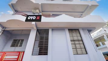 Un hotel chiamato 'OYO Hotel Raman' con un design architettonico moderno, caratterizzato da imponenti colonne verticali e ampie finestre.