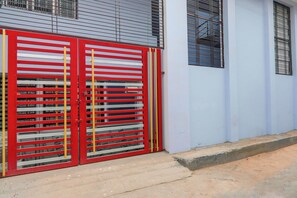 Un edificio con un portón rojo y amarillo, una pared azul y una ventana con barrotes.