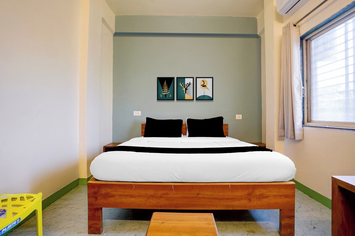 A bedroom with a wooden bed, a nightstand, a window with curtains, and three wall-mounted artworks.