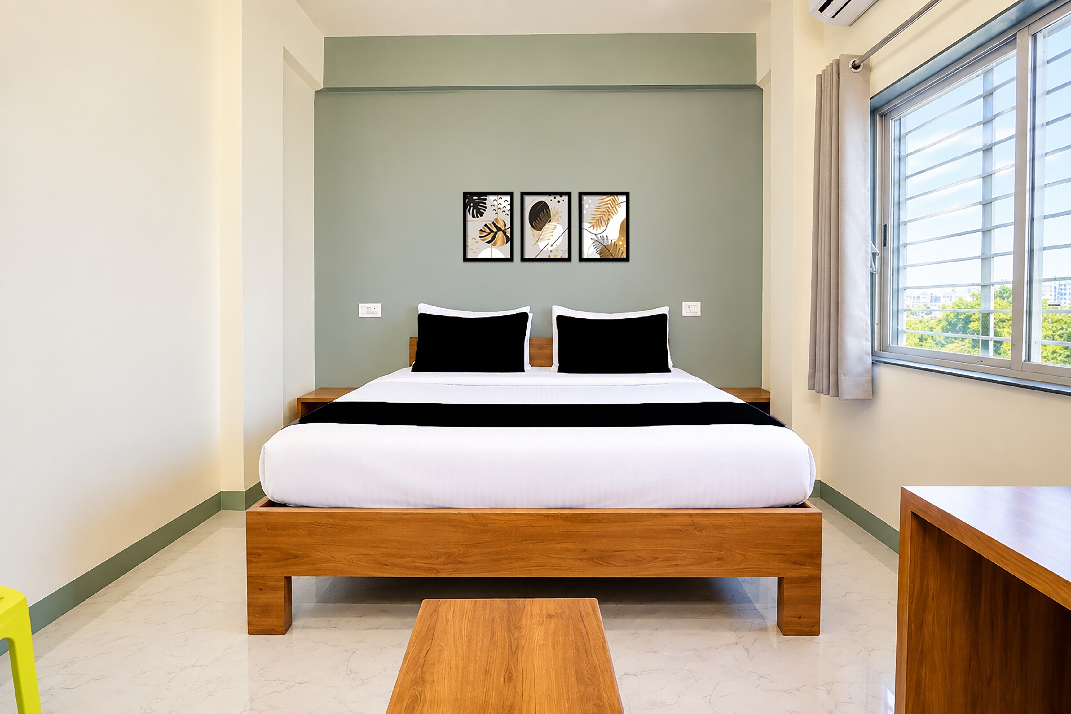 A bedroom with a bed, a wooden bench, and a window with blinds.