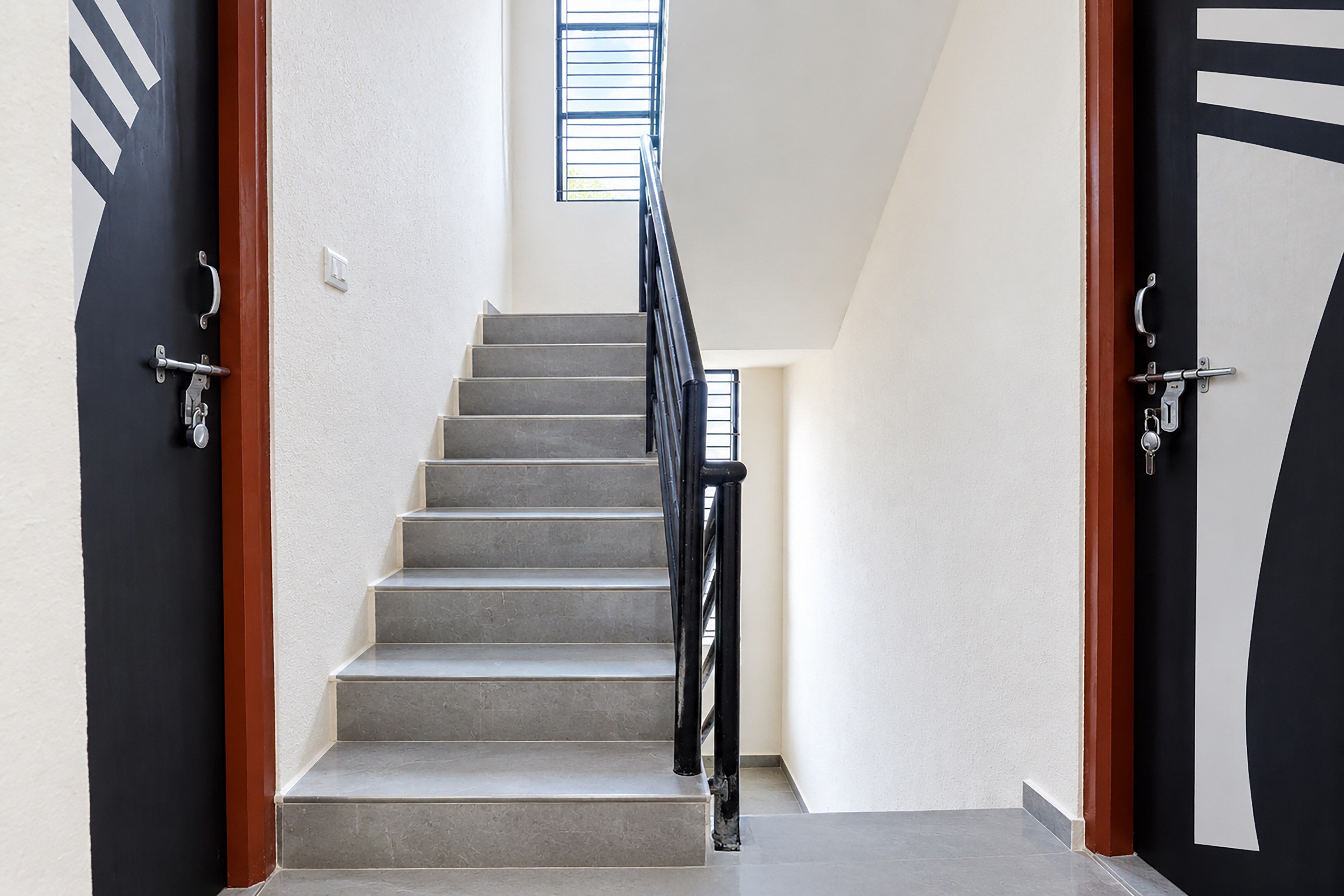 A staircase with a handrail, leading to a landing with a window.