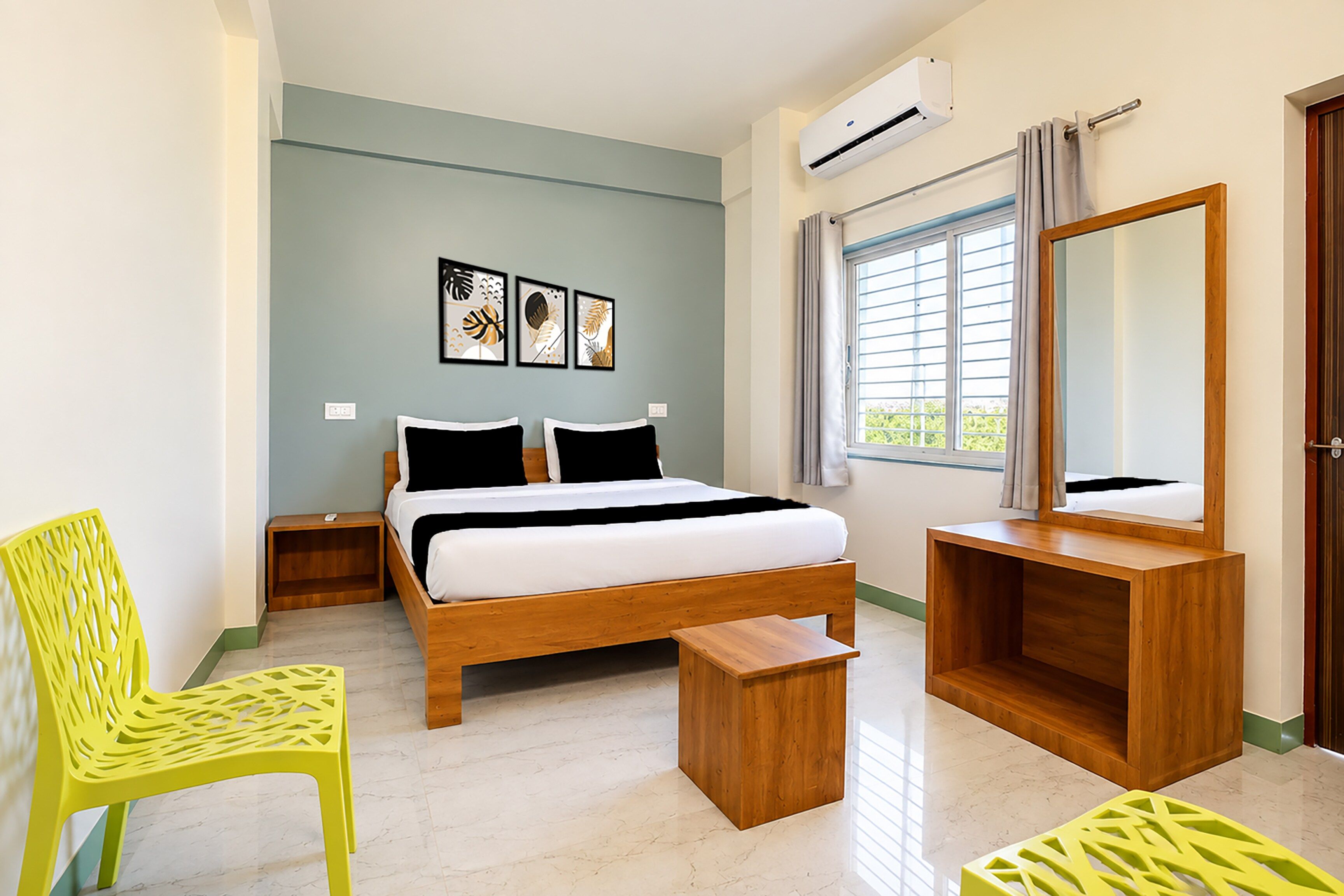 Une chambre à coucher avec un lit, des tables de chevet, une chaise, un miroir et des œuvres d’art accrochées au mur.