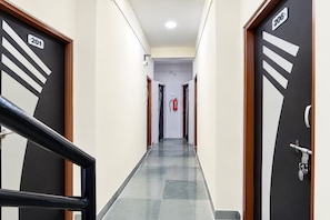 A hotel corridor with doors numbered 201 and 206, a fire extinguisher, and a metal railing. - Hotel O Aura Inn (Chhatrapati Sambhajinagar)