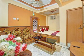 A hotel room with a bed, a wooden dresser, a glass coffee table, and a floral arrangement. - Hotel O Dream Plaza (Aurangabad - Bihar)