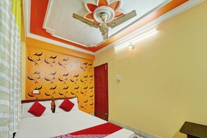 A hotel room with a bed, a ceiling fan, a wall with a decorative pattern, and a door. - Hotel O Dream Plaza (Aurangabad - Bihar)