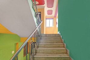 Eine Treppe mit Metallgeländern und Handlauf, die zu einer Zwischenebene mit einer Tür führt.