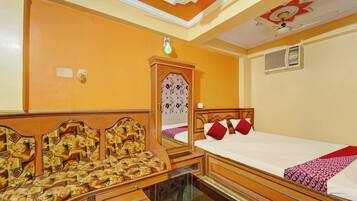 A hotel room with a bed, a mirror, a wardrobe, and a ceiling with decorative elements.
