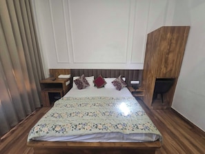 A neatly made bed with a floral bedspread, wooden headboard, and bedside tables with lamps and a phone. - Hotel O Lotus divine (Amritsar)