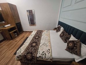 A bedroom with a bed, pillows, a wooden wardrobe, and a small window. - Hotel O Lotus divine (Amritsar)