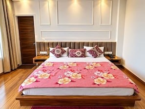 A bed with a floral bedspread, a headboard with a light-colored panel design, and two bedside tables with lamps. - Hotel O Grand Park (Amritsar)