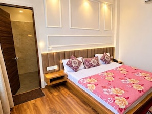A bedroom with a bed, bedside tables, and a wooden floor. - Hotel O Grand Park (Amritsar)