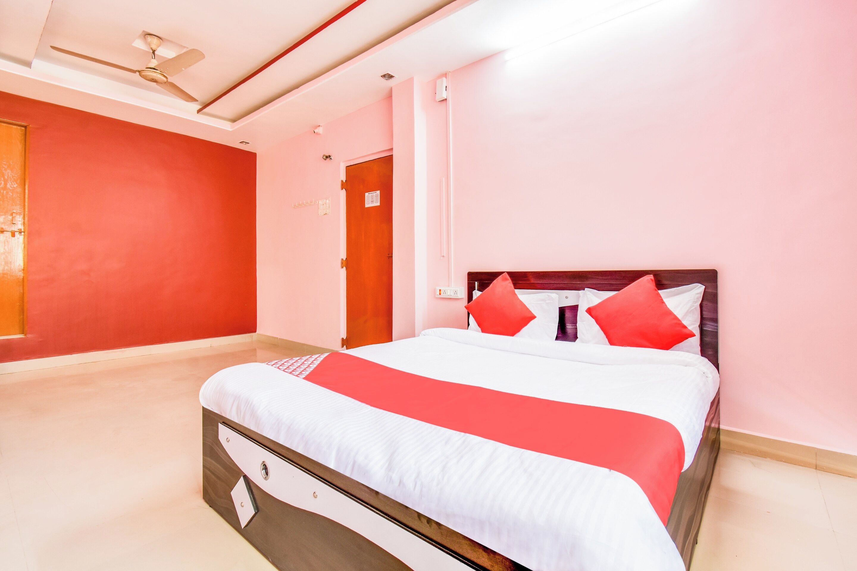 A hotel room with a bed, a ceiling fan, and a door with a sign.