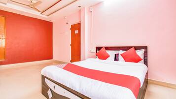A hotel room with a bed, a ceiling fan, and a door with a sign.