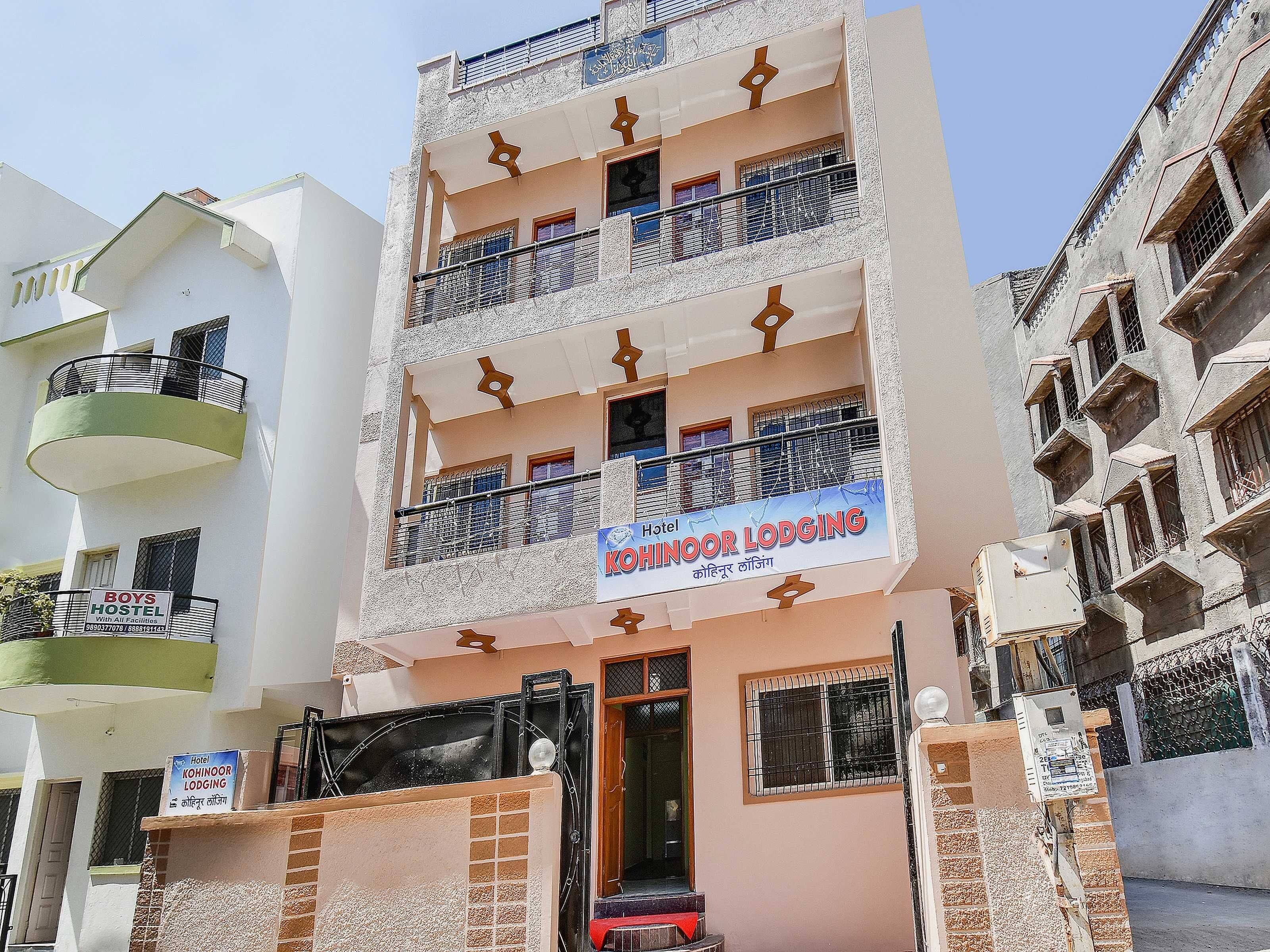 A multi-story hotel with balconies, a signboard for 'Hotel Kohinoor Lodging,' and a 'Boys Hostel' sign.
