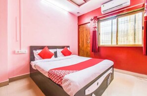 A bedroom with a bed, a window with curtains, and an air conditioning unit.