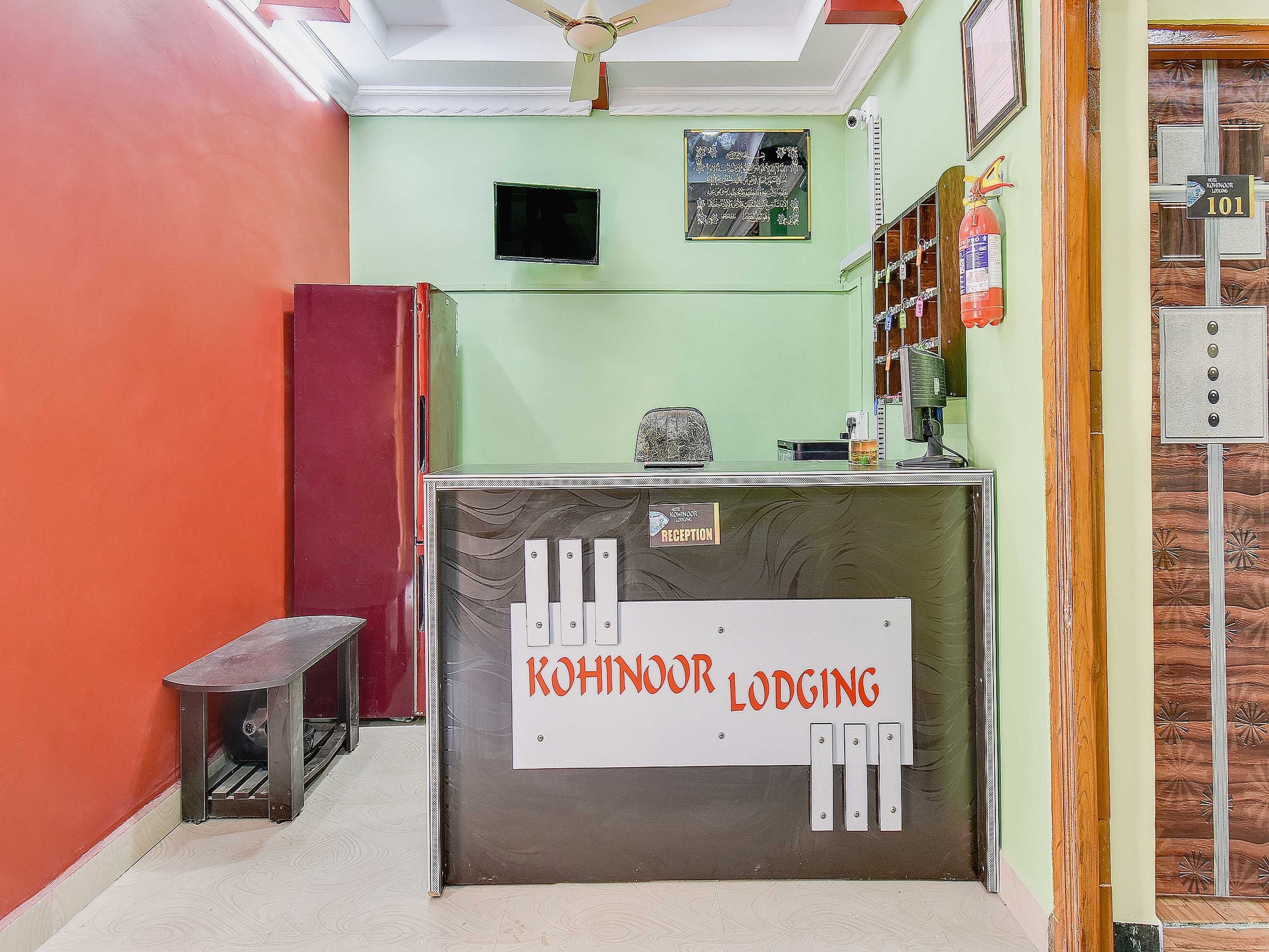 Una recepción con un cartel de Kohinoor Lodging, un extintor y un televisor montado en la pared.