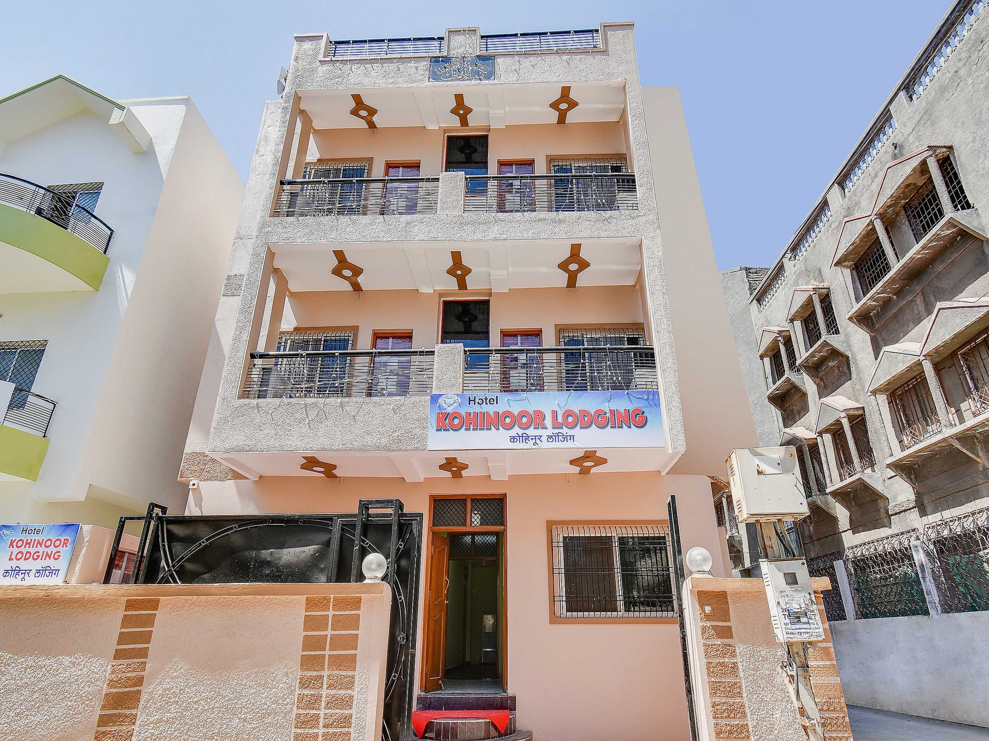 A multi-story hotel with balconies, a signboard, and a gated entrance.