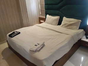 A neatly made bed with a folded towel and a remote control on the bedspread. - Hotel O IJ Grand (Amritsar)