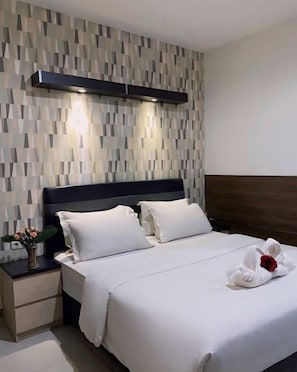 Habitación de hotel con cama, mesitas de noche y una pared con diseño geométrico.