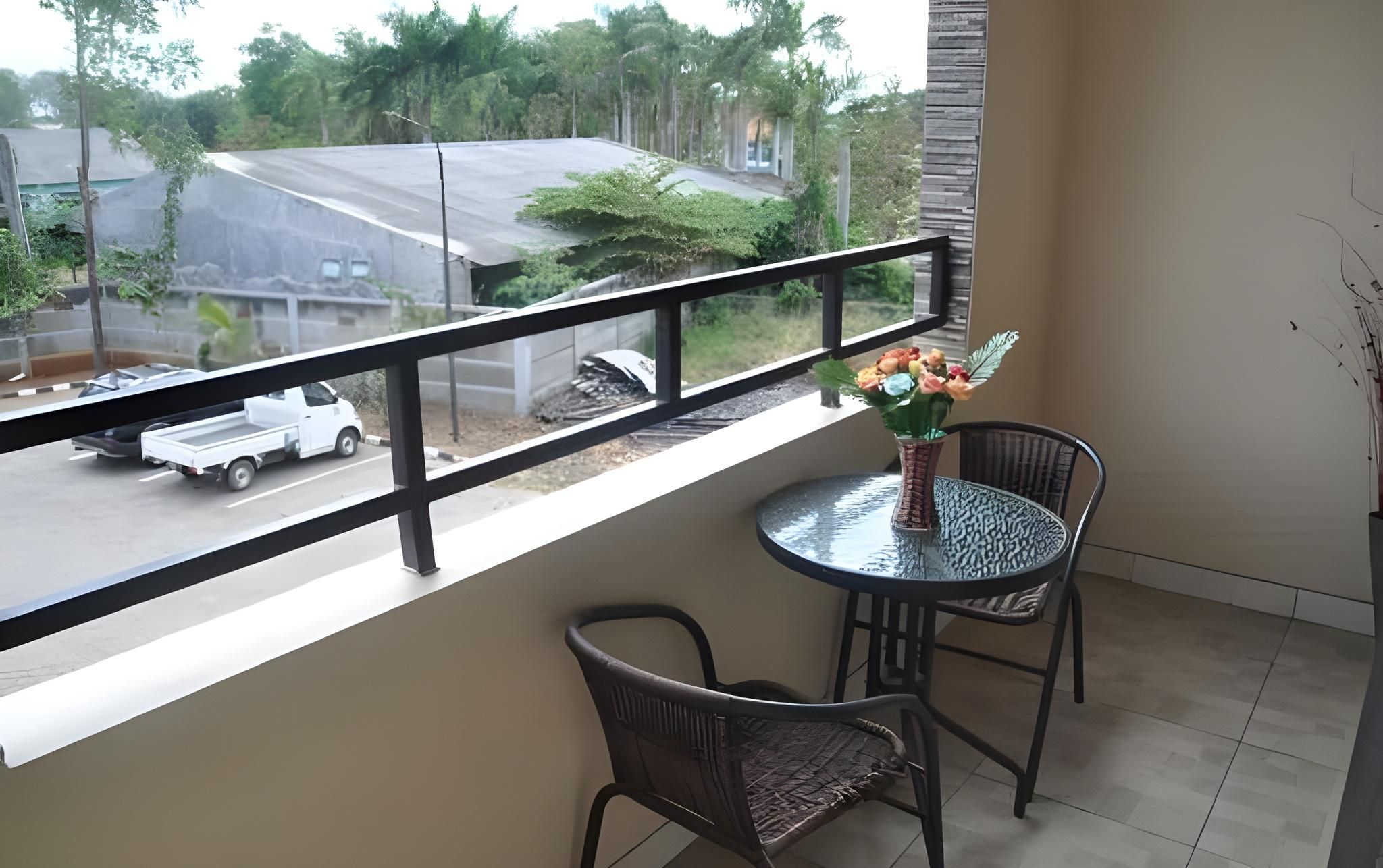 A balcony with a table and chairs, overlooking a street with a parked truck.
