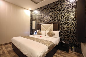 A hotel room with a large bed, a nightstand, a lamp, and a wall with a decorative pattern. - Hotel O chohan residency (Amritsar)